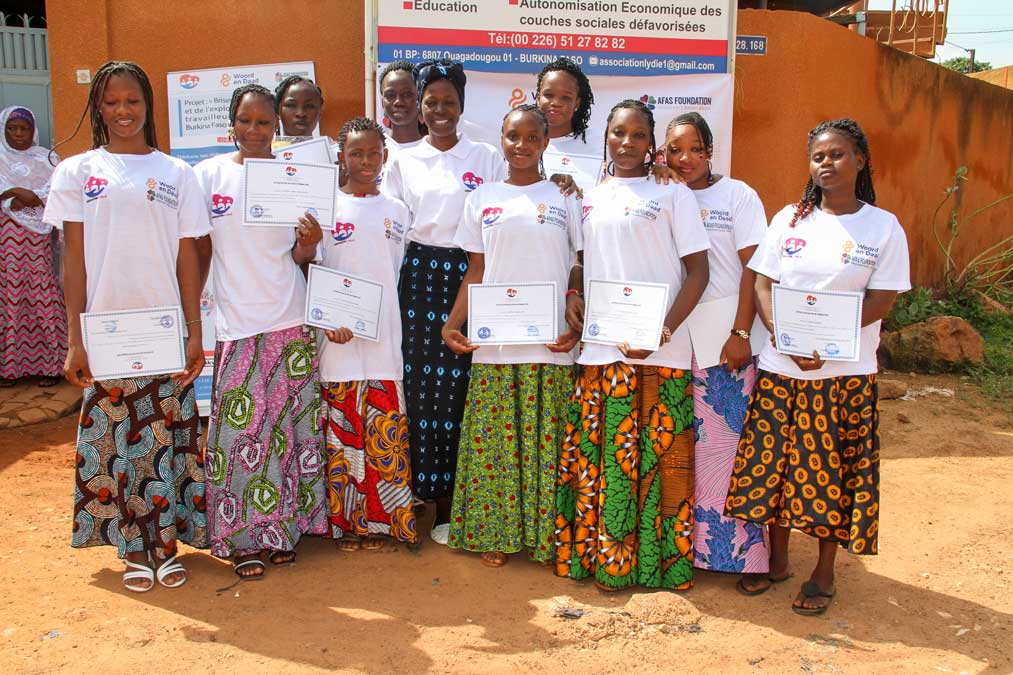 Jeunes femmes bénéficiaires diplômées présentant fièrement leurs attestations de formation devant le siège de LYDIE